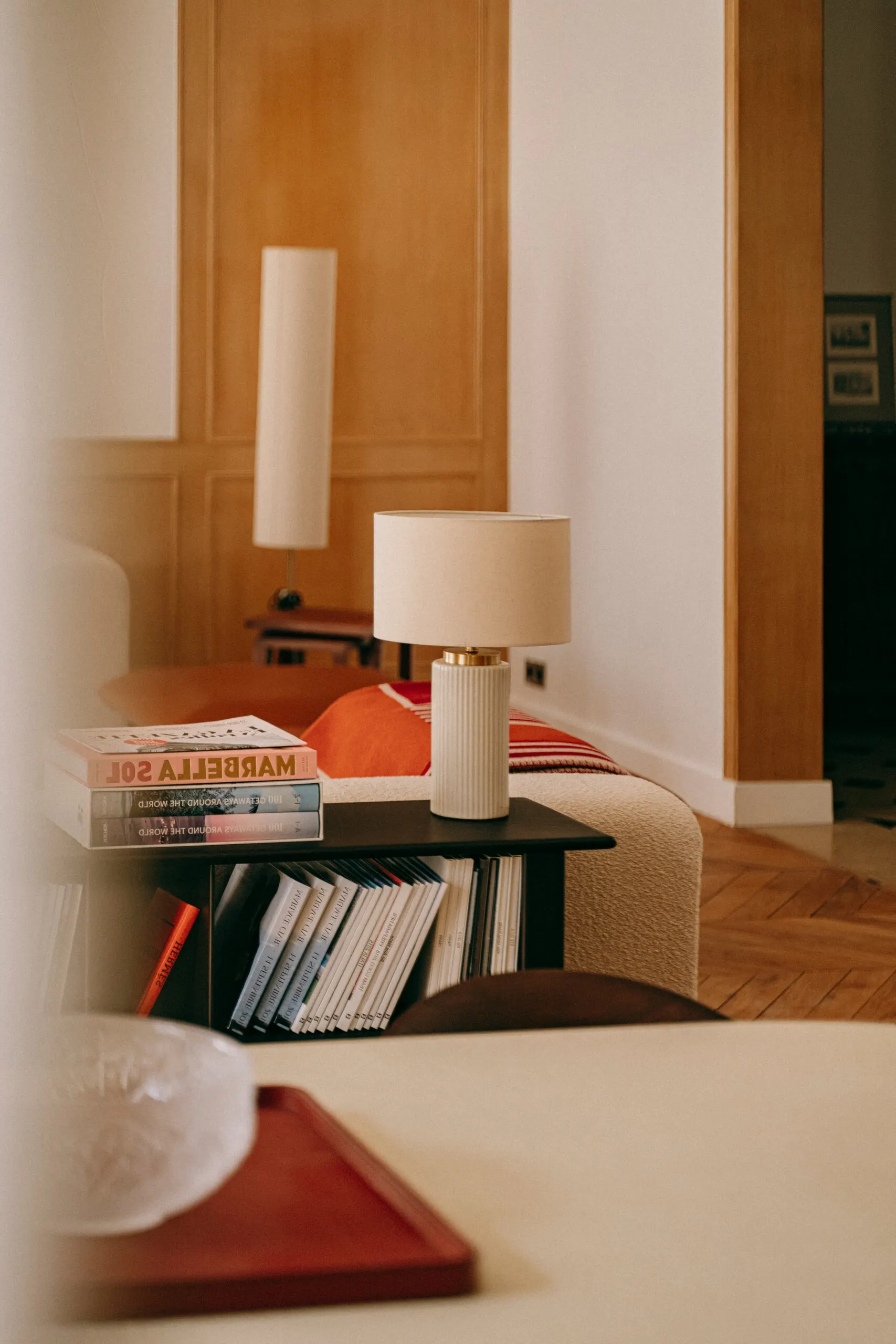 Détail : lampe et livres devant un habillage en bois blond